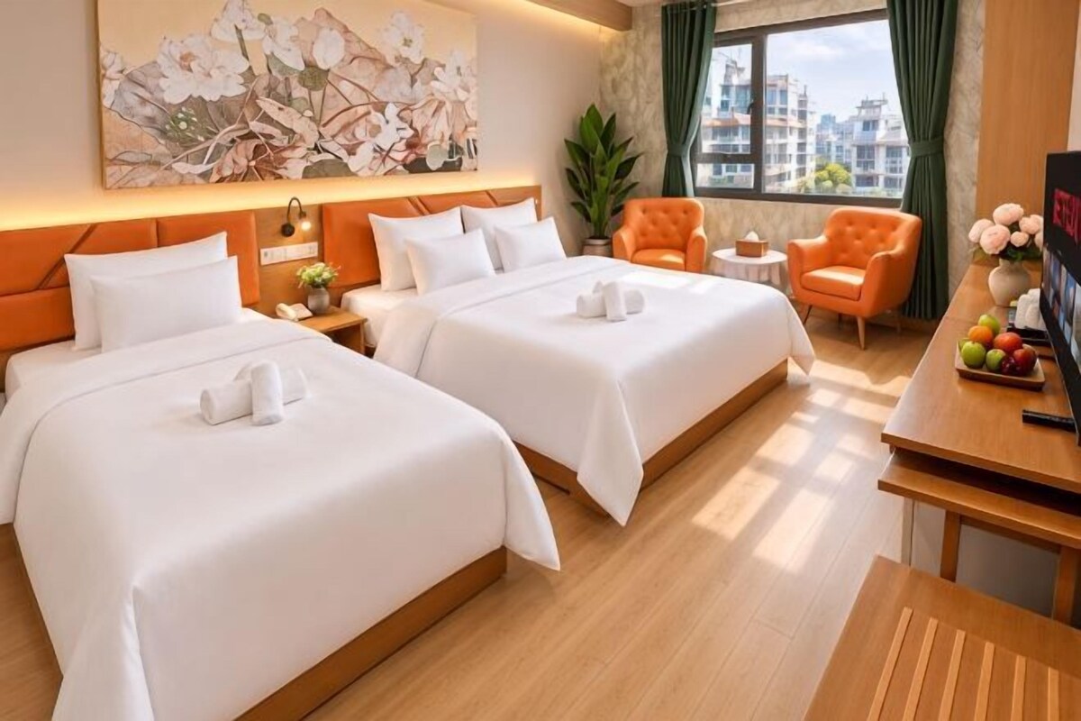 Une chambre d’hôtel avec deux lits, un bureau, une chaise et une grande fenêtre donnant sur la ville.