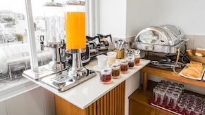 Ein Frühstücksbuffet mit Kaffeemaschine, Saftspendern und einer Auswahl an Speisen.