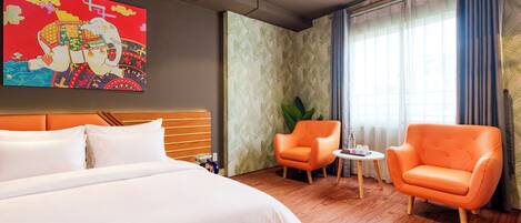 Ein Hotelzimmer mit einem großen Bett, zwei Sesseln, einem kleinen Tisch und einem Wanddekor.