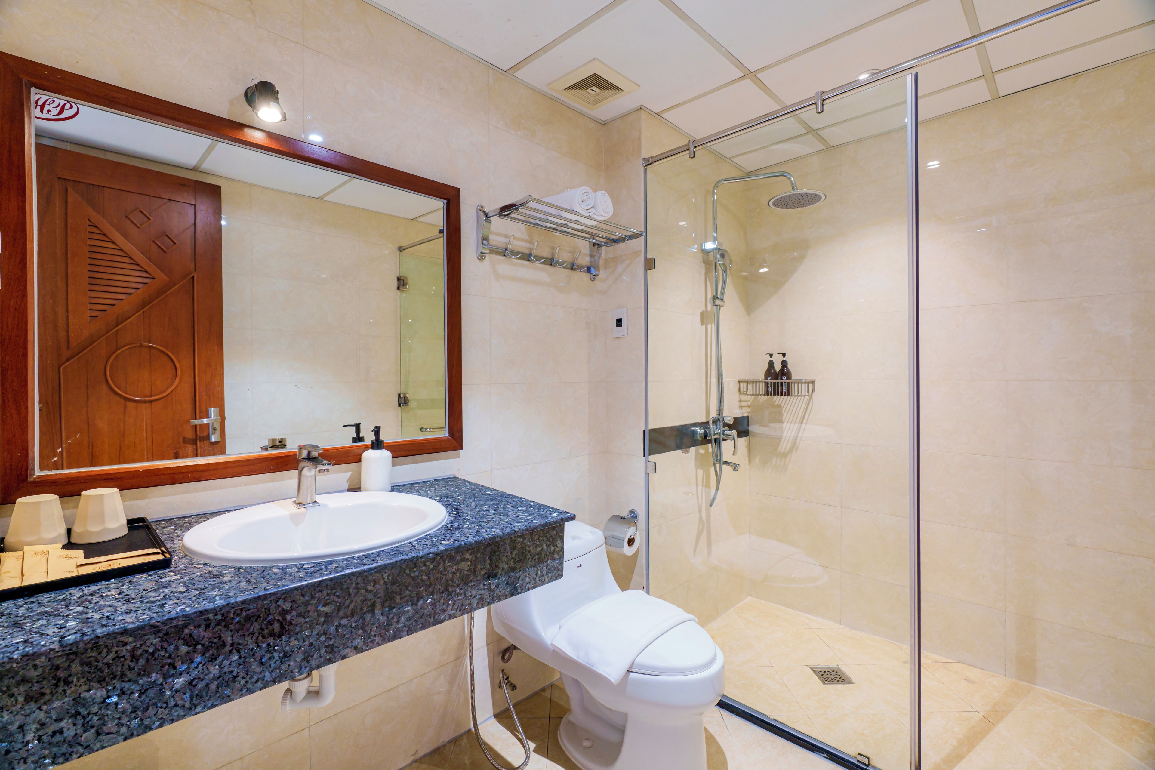 A modern bathroom with a glass-enclosed shower, a sink with a marble countertop, and a toilet.