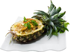 Un ananas surmonté d’une salade, le tout présenté sur une assiette blanche.