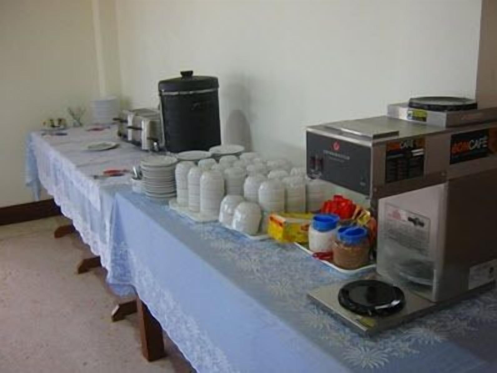 A buffet setup with plates, bowls, and a coffee machine.