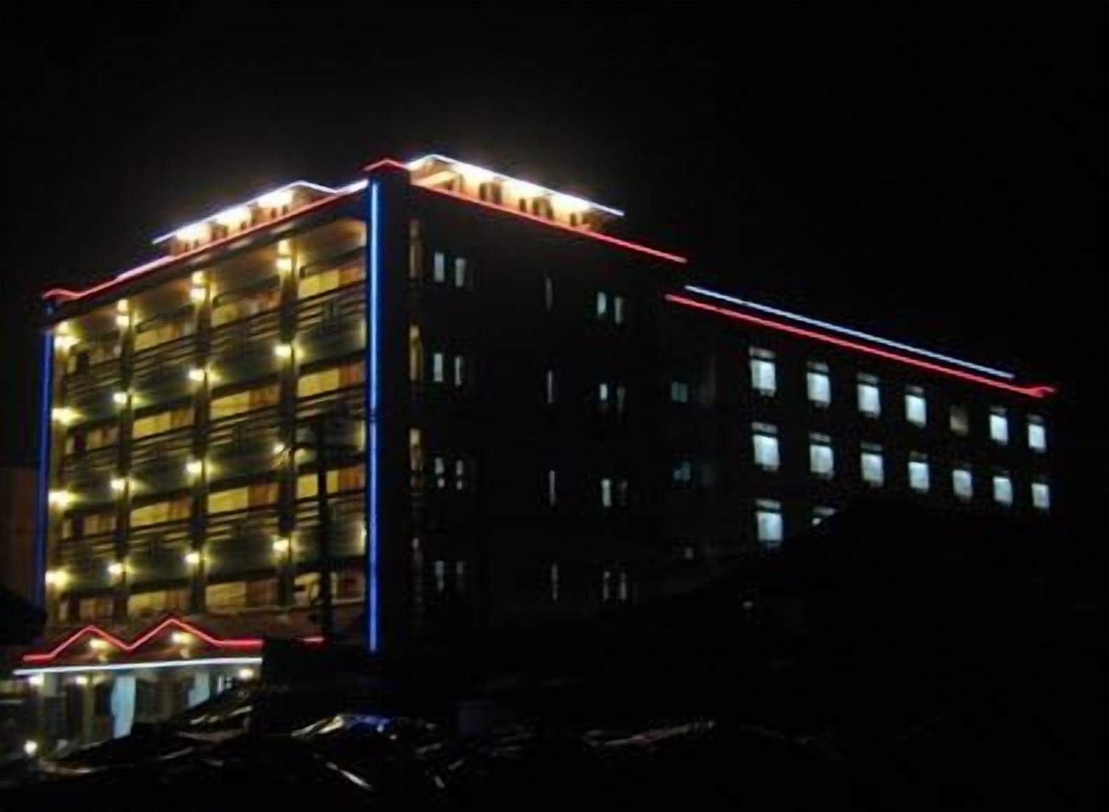 A multi-story building with a modern design, featuring a series of balconies and a prominent red and blue neon outline.