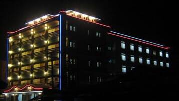 Um edifício de vários andares com design moderno, apresentando uma série de varandas e um contorno neon vermelho e azul bem visível.