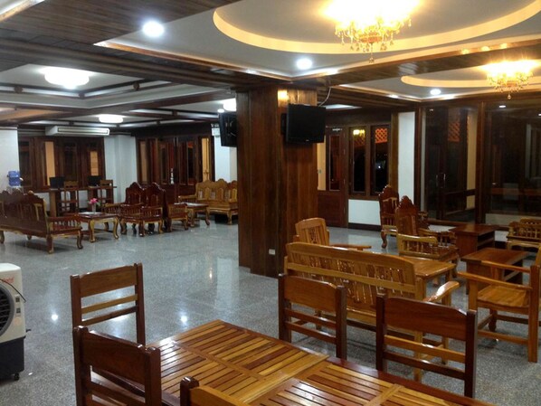 A spacious room with wooden furniture, including tables and chairs, and a chandelier.
