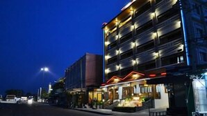 Un hotel de varios pisos con un restaurante en la planta baja y terraza al aire libre.