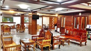 Un hall amplio con mobiliario de madera, incluyendo sofás y sillones, y un suelo pulido.