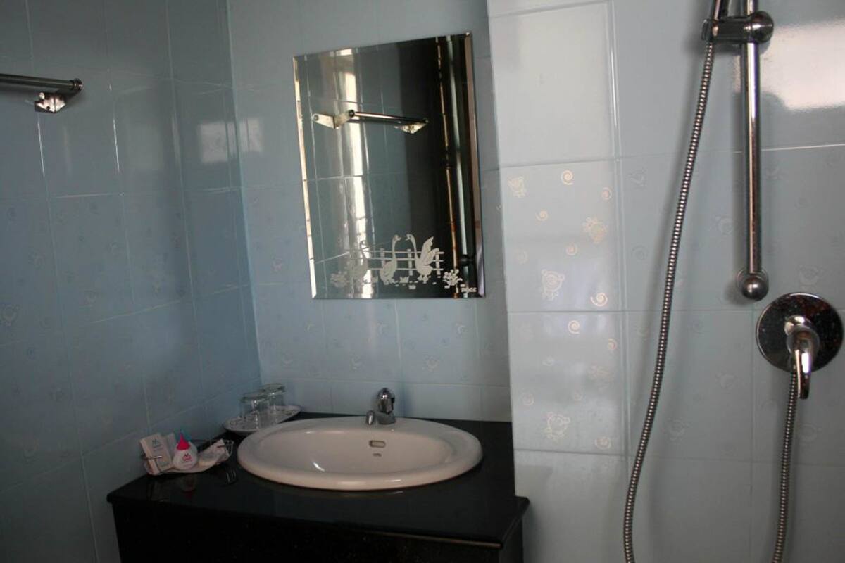 A bathroom with a sink, mirror, and shower.