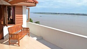 Un banco de madera en un balcón con vista a una masa de agua tranquila.