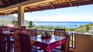A dining area with a table set for two, overlooking a scenic ocean view.