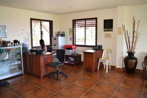 Una oficina con dos escritorios, sillas, una computadora y un ventilador.
