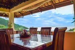 Una mesa de comedor con sillas, vista al mar y un paisaje montañoso.