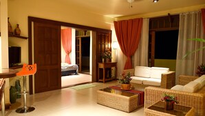 A living room with a sofa, a coffee table, a television, and a door leading to another room.