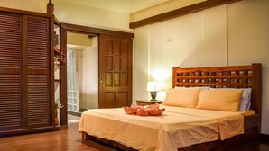 A neatly made bed with a wooden headboard, a bedside table with a lamp, and a wooden wardrobe.