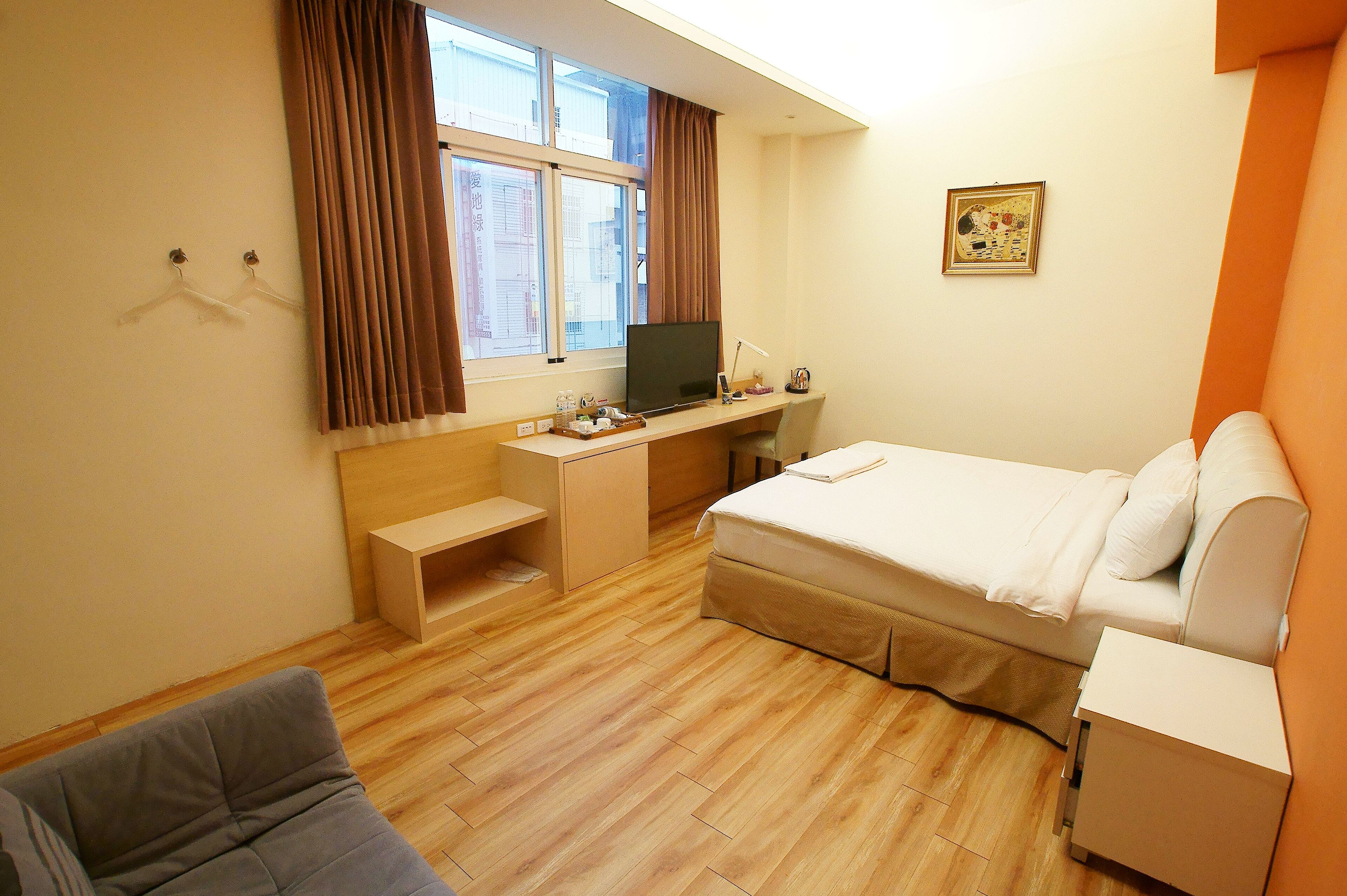Ein Hotelzimmer mit Bett, Schreibtisch, Stuhl und einem fenster mit Vorhängen.