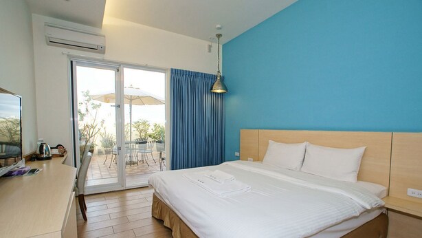 A hotel room with a bed, a desk, and a view of the outdoors. - Venice B&B (Taitung)