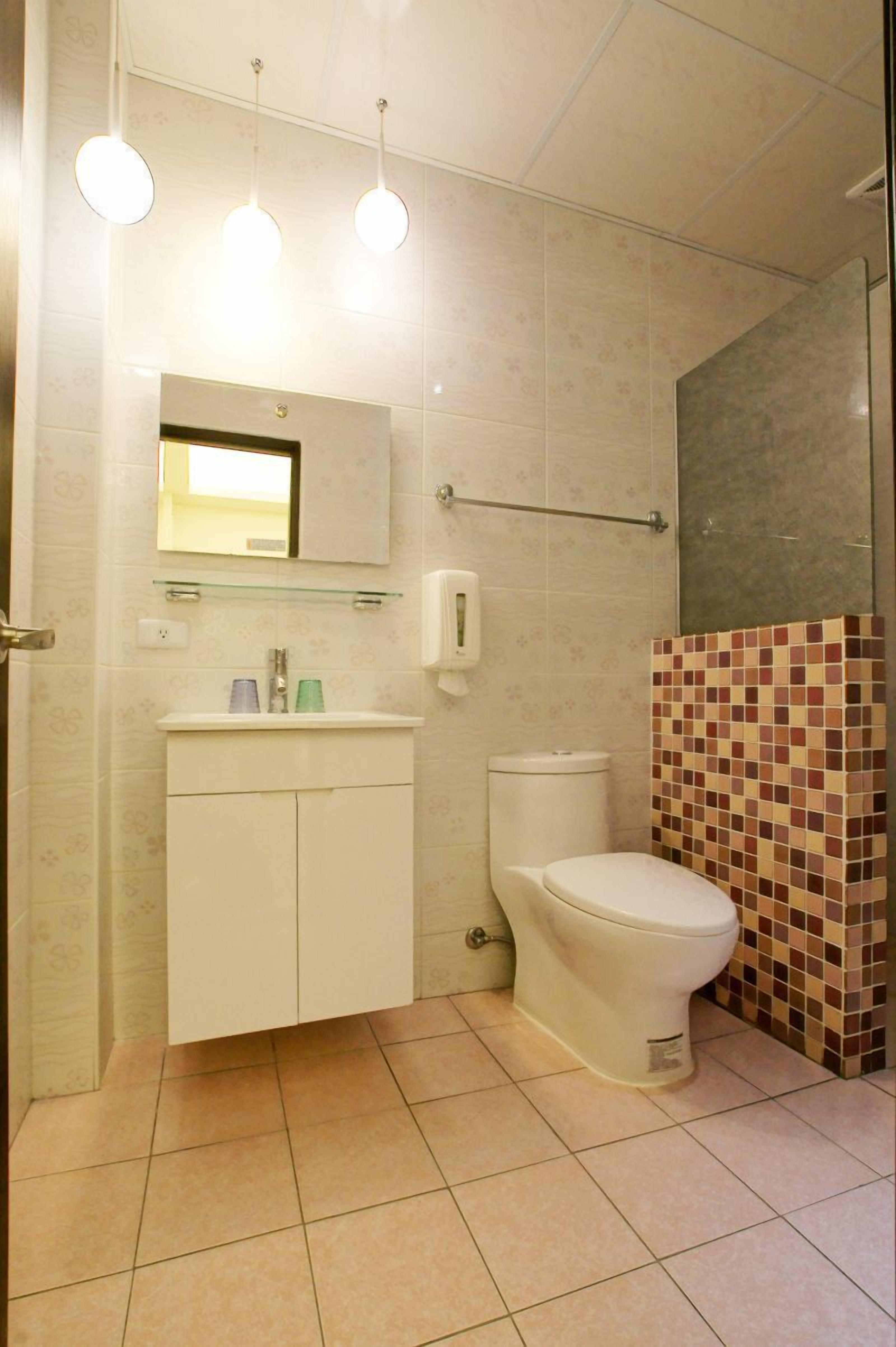 A bathroom with a toilet, sink, and mirror.