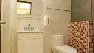 A bathroom with a toilet, sink, and mirror.