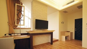 A modern living room with a flat-screen TV on a wooden stand, a brick accent wall, and a wooden floor. - Venice B&B (Taitung)