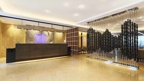 Una moderna zona de recepción con un mostrador, una pared decorativa con diseños circulares y una estructura de columna negra y blanca distintiva.