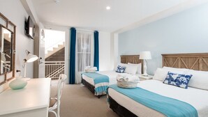A hotel room with two beds, a desk, and a staircase.