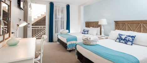 Une chambre d’hôtel avec deux lits, un bureau et un escalier.
