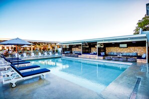 A pool area with lounge chairs and a stone wall seating area. - Rambutan Resort (Townsville)