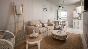 A cozy living room with a beige sofa, a wooden ladder, a round coffee table, and a wicker chair. - Rambutan Resort (Townsville)