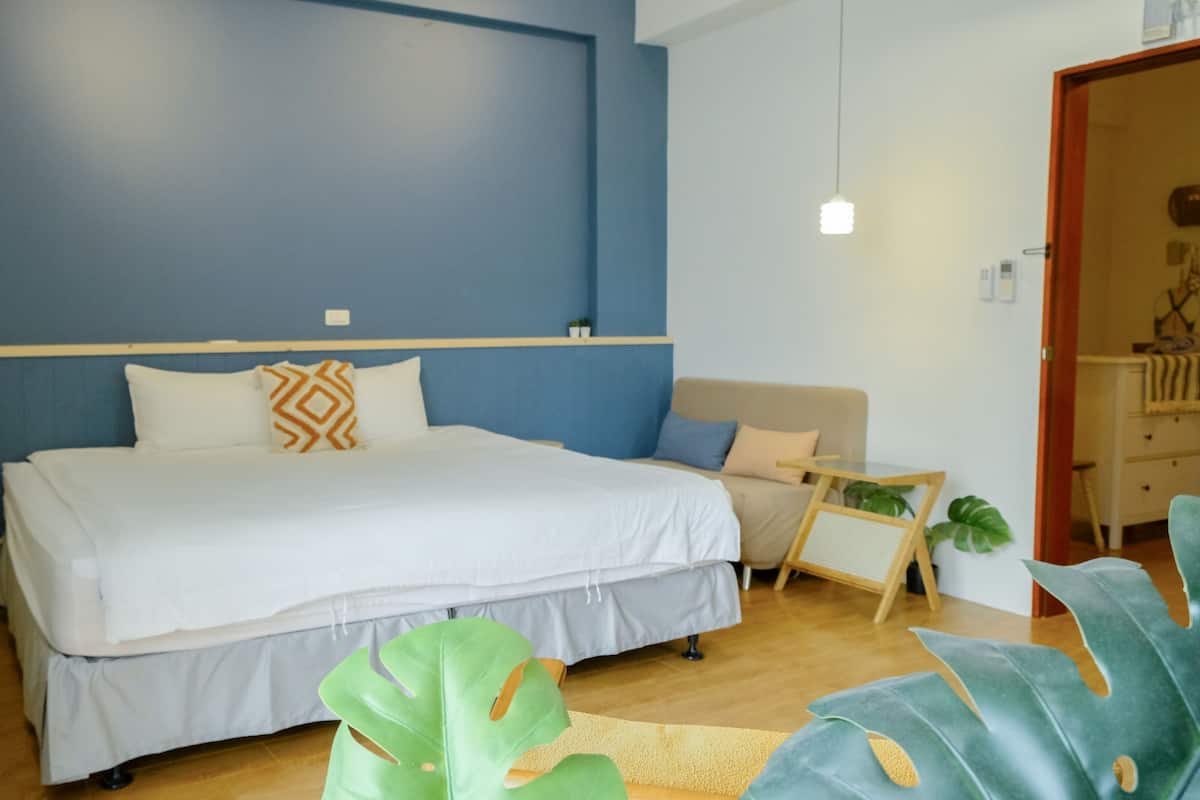 Een slaapkamer met een bed, een bank en een grote plant.
