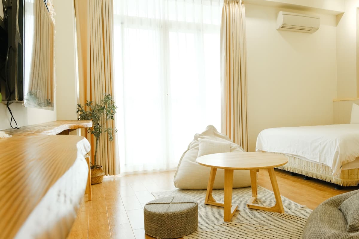 Een moderne hotelkamer met een bed, een klein rond tafeltje, een sofa en een plant in pot.