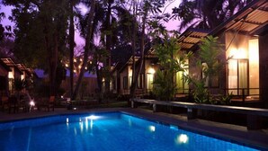 Una piscina rodeada de palmeras y un edificio con un patio techado.