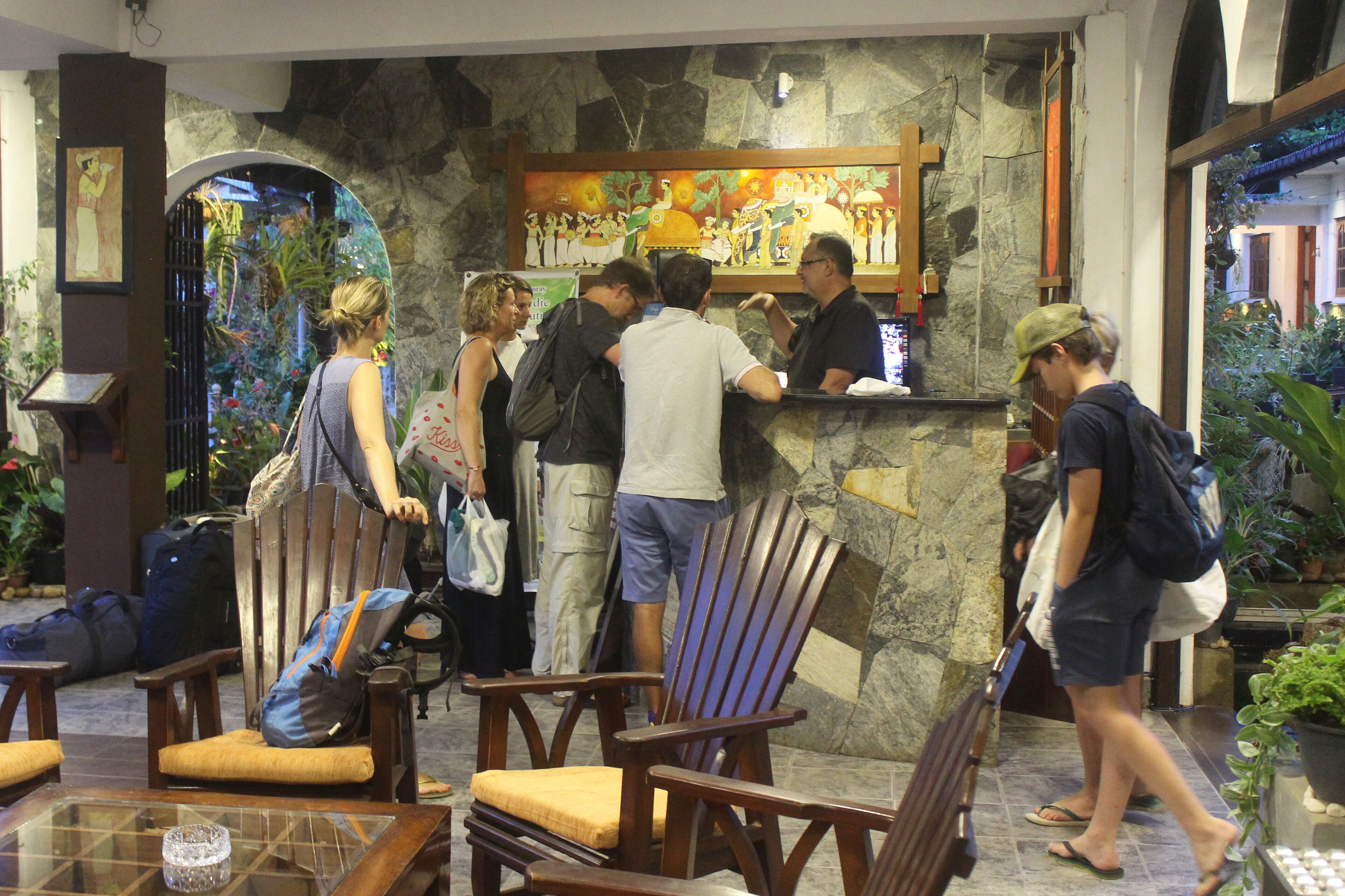 A lobby with wooden chairs, a reception desk, and a stone wall with a mural.