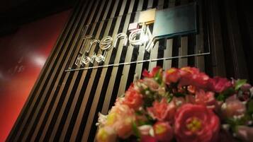 Un letrero de hotel con el nombre 'Trend' y un arreglo floral en primer plano.