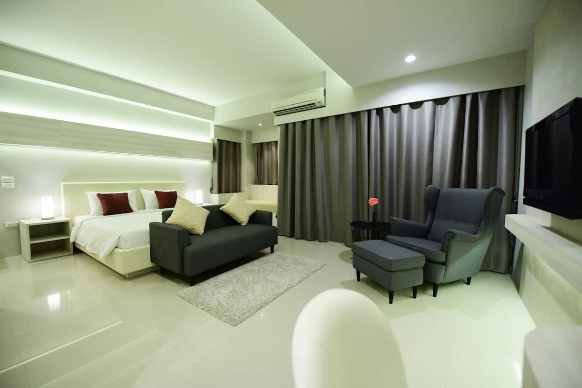Una habitación de hotel moderna con cama, sofá, sillón y televisor.