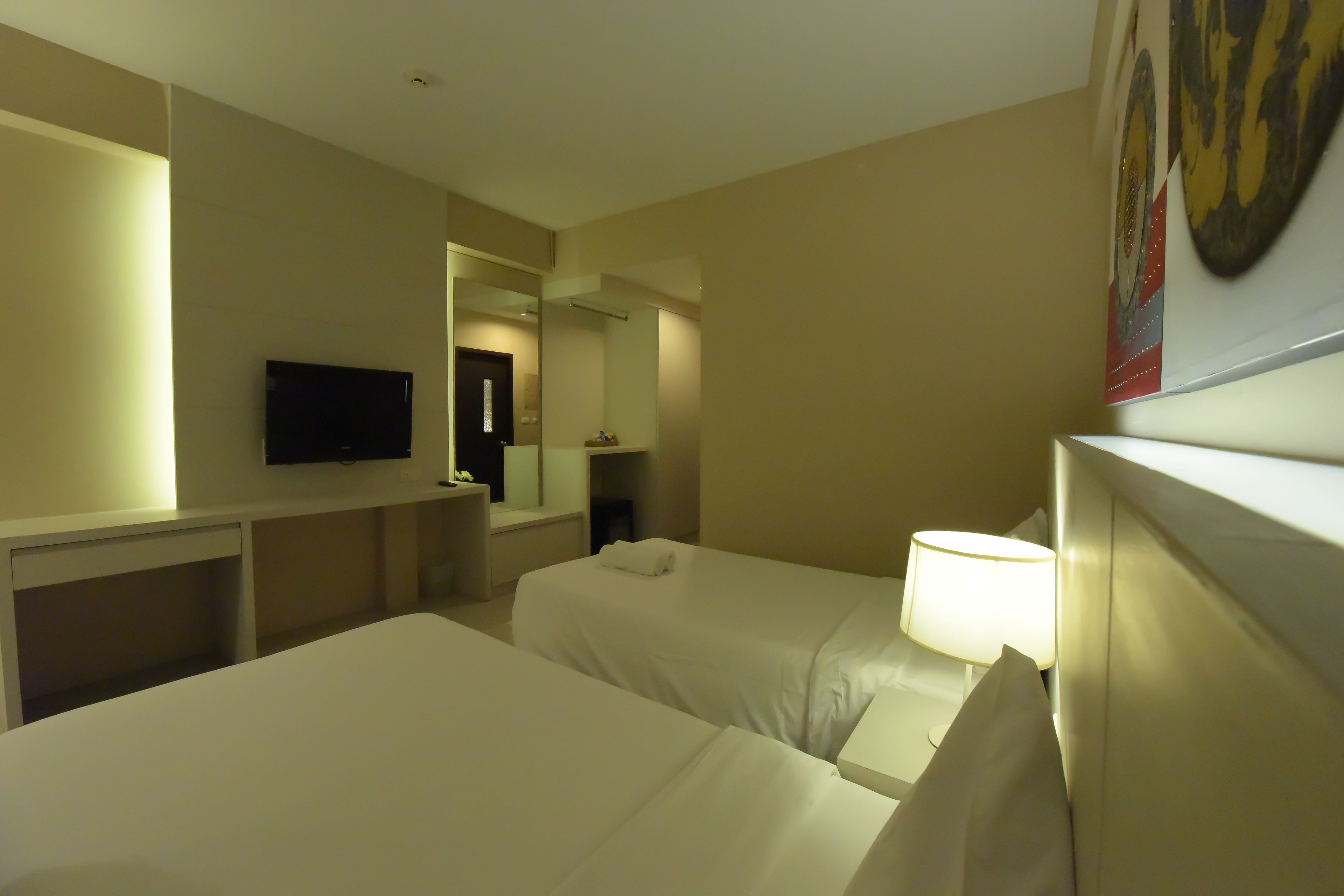 Une chambre d’hôtel avec deux lits, une télévision, un miroir et une lampe.