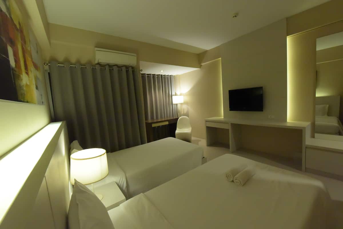Una habitación de hotel con dos camas, un escritorio, un televisor y un baño con cortinas.