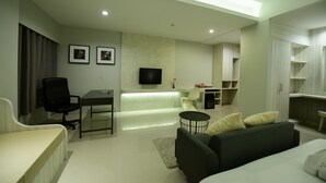 Una sala de estar moderna con un sofá, una mesa de comedor, un televisor y una zona de cocina.