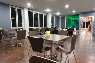 Un comedor moderno con mesas y sillas, ventanas amplias y vistas al exterior.