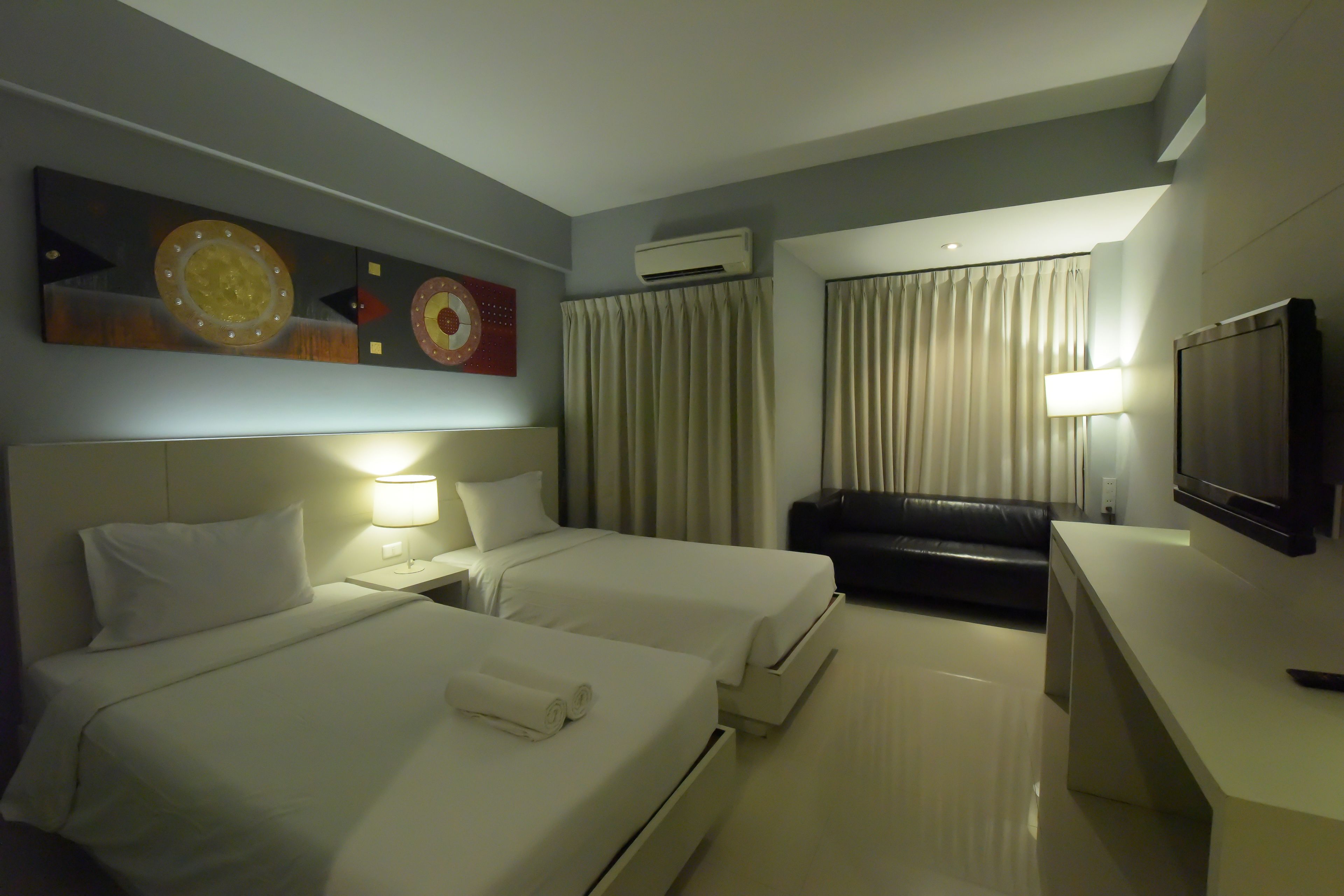 Una habitación de hotel con dos camas, televisión, escritorio y sofá.