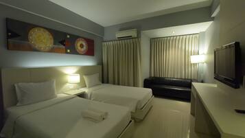 Una habitación de hotel con dos camas, televisión, escritorio y sofá.