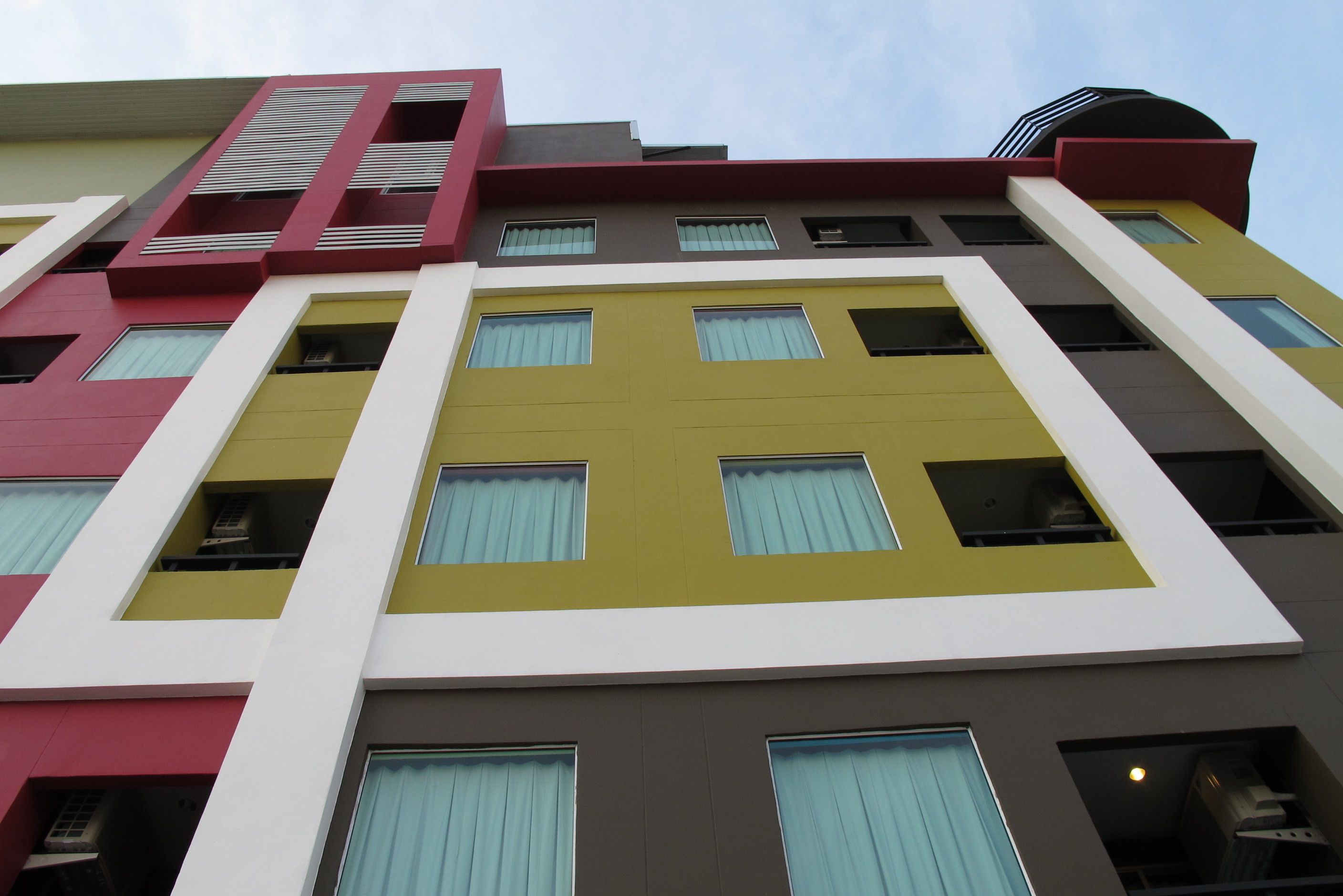 A multi-story building with a modern architectural design, featuring a mix of red, yellow, and white colors.