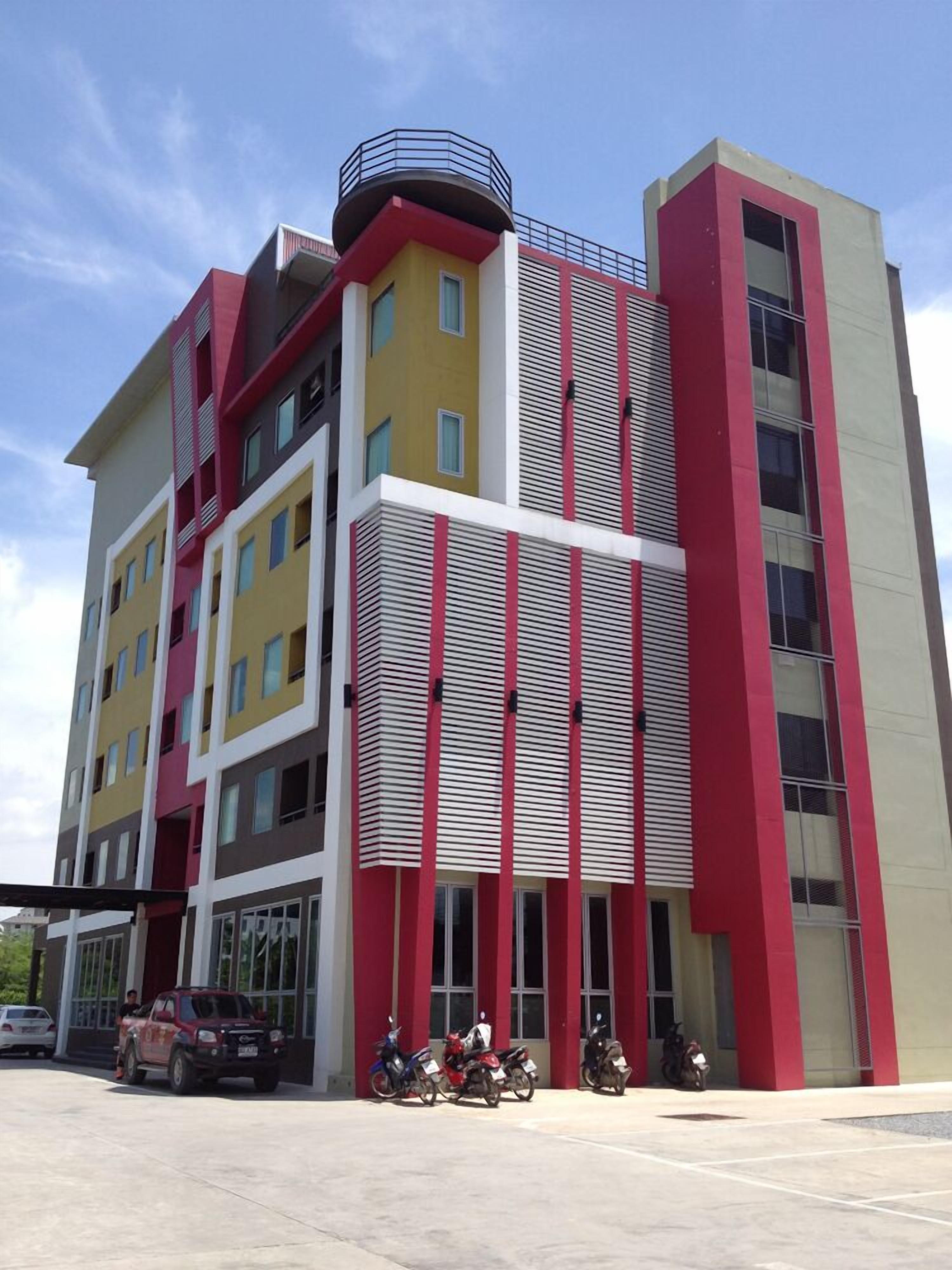 A multi-story building with a modern architectural design, featuring a mix of yellow, red, and white colors.
