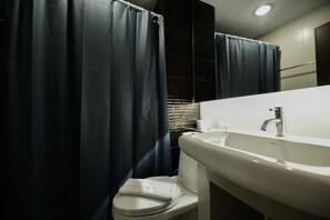 Un baño con un lavamanos blanco, un inodoro y cortinas azul oscuro.