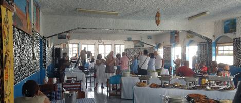 A restaurant with a high ceiling and patterned walls, featuring a buffet setup with various dishes.
