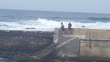 A stone pier extending into the ocean with two people standing at the end.