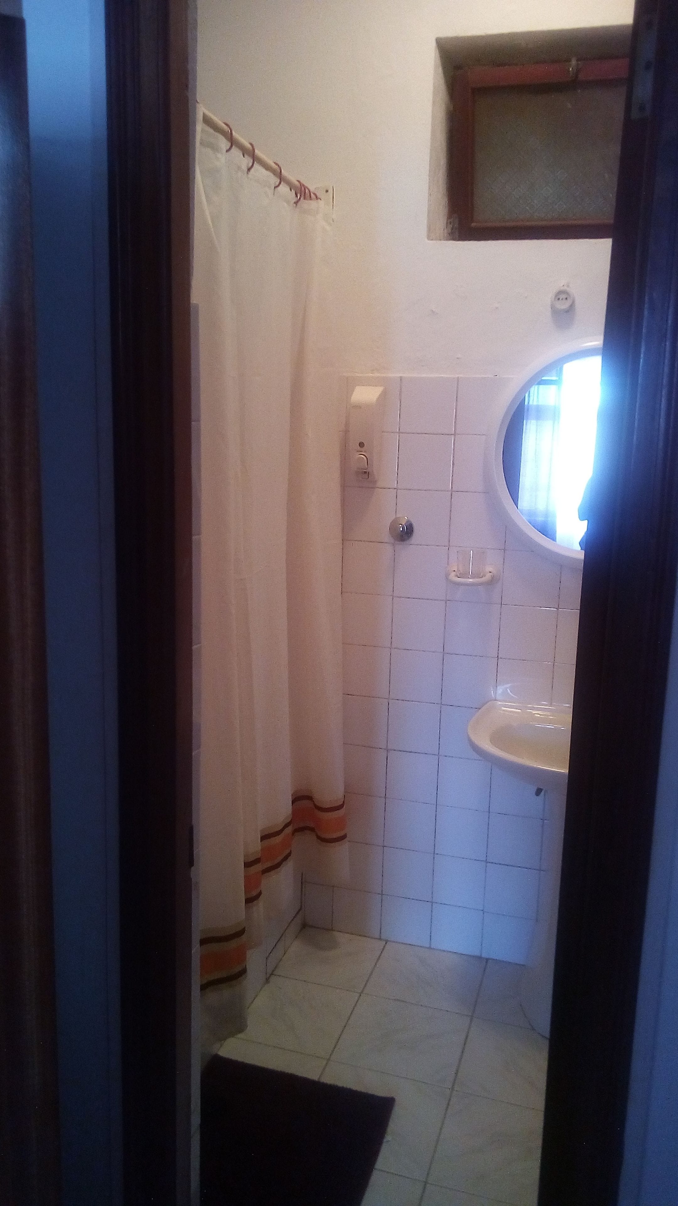Un baño pequeño con ducha, lavamanos y ventana.