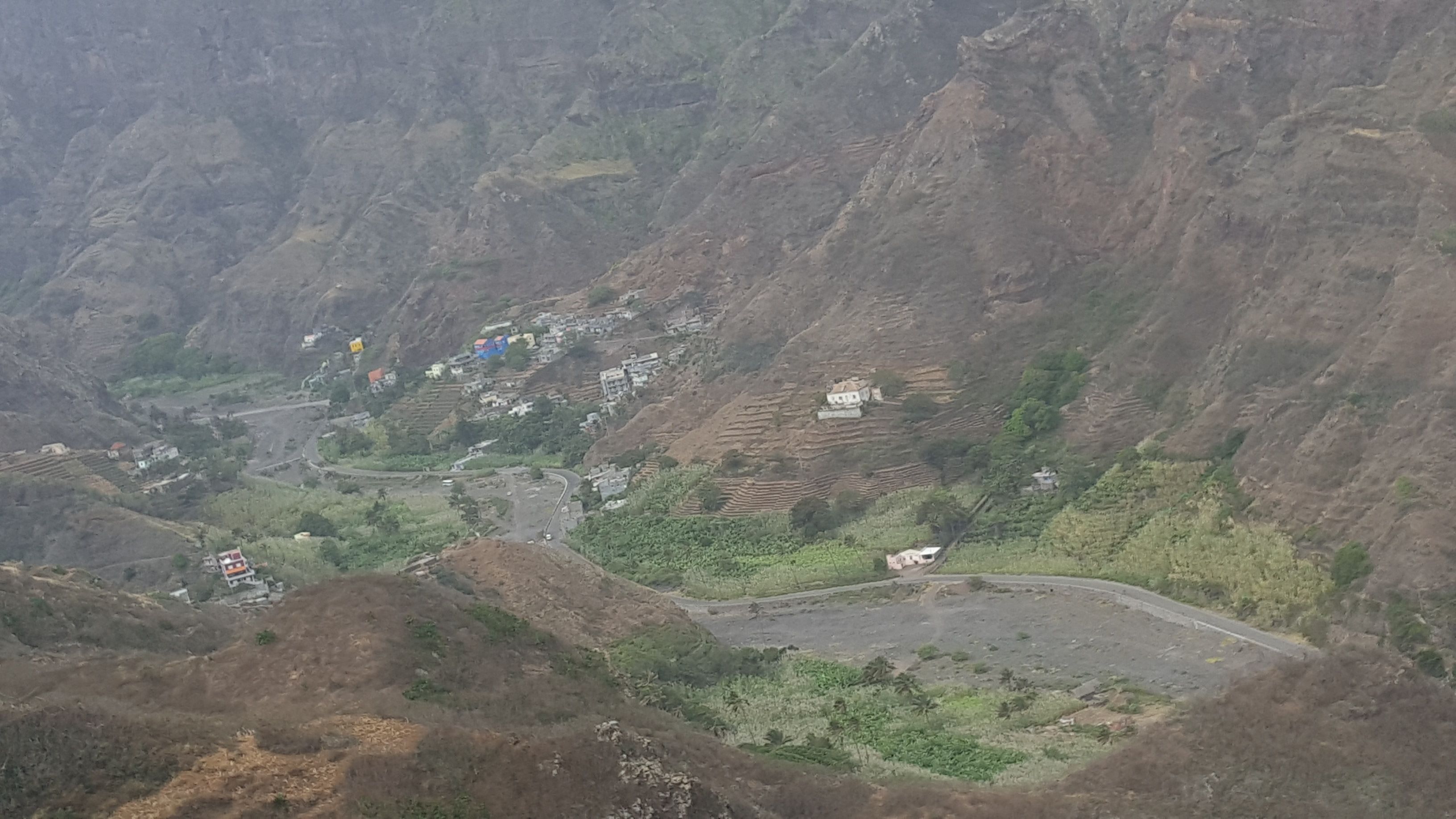 A mountainous landscape with terraced fields and scattered buildings.