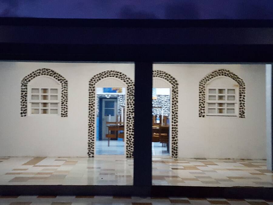 A hallway with three arched doorways, each with a patterned design. The floor is tiled with a checkered pattern.