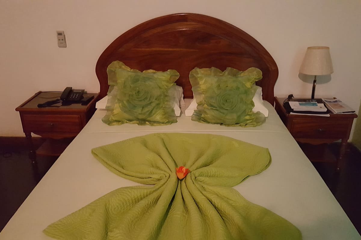 A neatly made bed with a green blanket and a decorative pillow arrangement.
