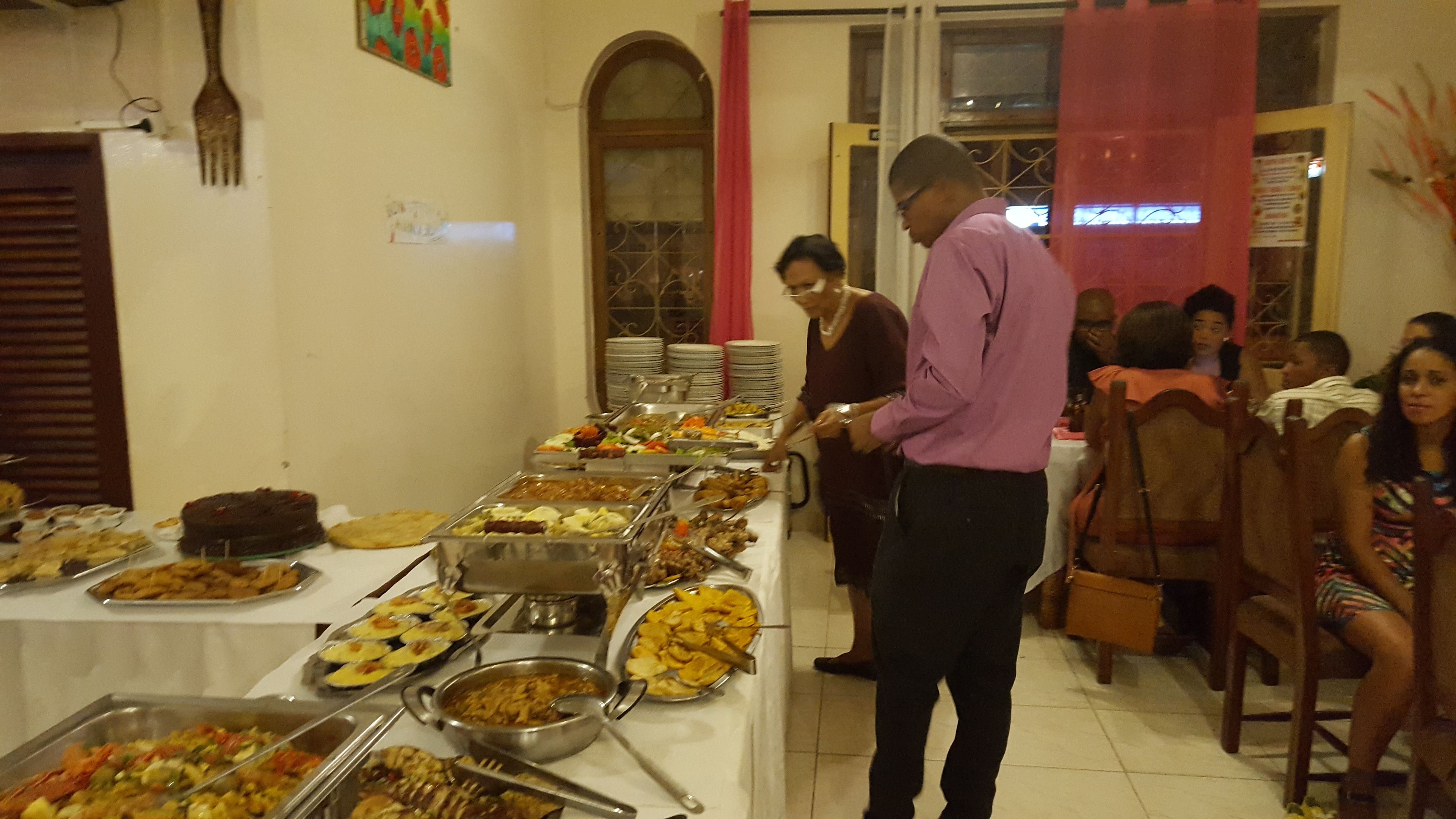 Montaje de bufé con diferentes alimentos en bandejas y una persona sirviendo.